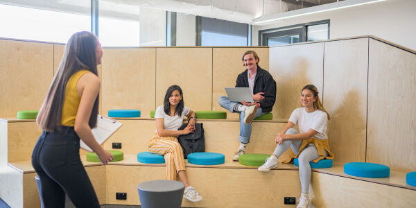 A group of student's together and one presenting to the rest of them